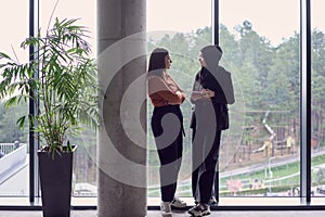 In a modern office a pair of colleagues, one wearing a hijab, engage in a lively discussion, sharing their business