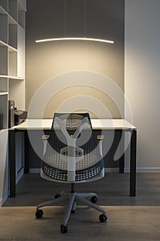 Modern office place with comfortable office workspace - computer desk, orthopaedic chair and right artificial light for