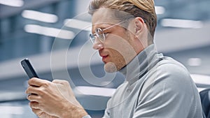 Modern Office: Portrait of Creative Businessman Sitting at His Desk Using Smartphone. Digital Entr