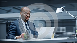 Modern Office: Successful Businessman Sitting at Desk Using Laptop Computer. African American Entr