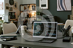 Modern Office Workspace Featuring Laptop Displaying Programming Code on Screen