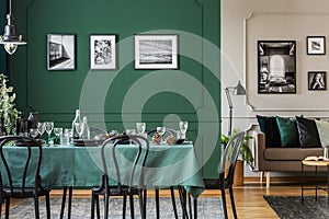 Modern, open space apartment interior with artistic, framed photos on green and white walls with molding. Real photo