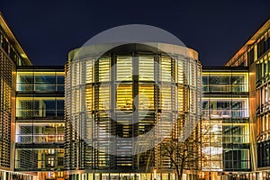 Modern opulent cylindrical office illuminated at night with sun blinds and side passageways features a contemporary massive facade