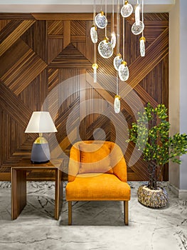 Modern orange armchair, lamp shade on small wooden table, contemporary tall glass chandelier, and wood cladding wall