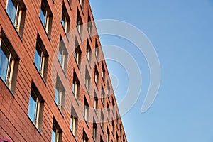 Modern orange bricked facade with windows against the sky is an example of building neat architecture. Modern orange exterior