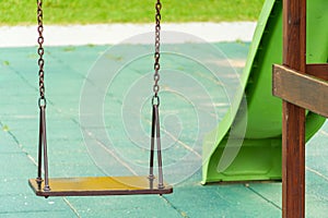 A modern outdoor playground in the courtyard of a building. Colorful children\'s swings and slides for recreation and games