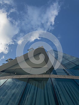 Modern palace architecture, reflective windows, glass palace. Sky mirrored in the windows of a building. Clouds in the sky, corner