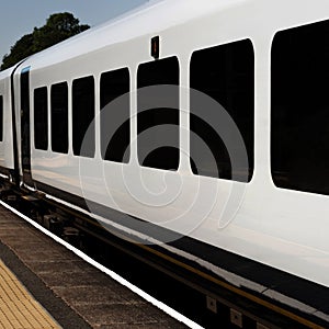 A modern passenger train painted white with darkened windows. UK