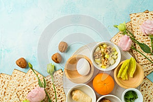 Modern Passover seder plate with matzah, spring flowers and orange for LGBTQ equality on blue background. Top view, flat lay