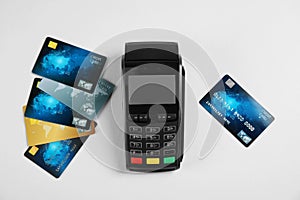Modern payment terminal and credit cards on grey background