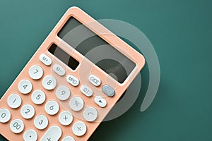 modern peach colour pastel calculator and white button on green background, business and finance concept