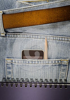 Modern phone in old blue jeans.