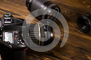 Modern photo camera and photo lenses on wooden table