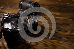 Modern photo camera and photo lenses on wooden table