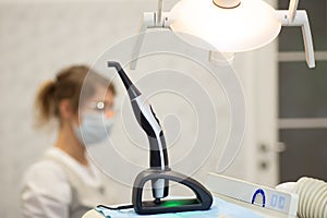 A modern photopolymerization lamp for light fillings in the dental office, on a blurred background