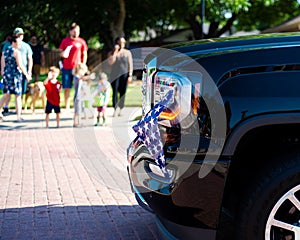 Modern pickup truck American flag near headlight bumper driving on residential street smalltown Fourth of July parade near Dallas