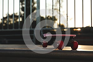Modern pink skateboard with red wheels on top of ramp outdoors. Space for text