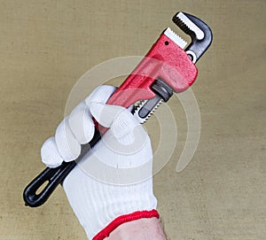 Modern pipe wrench in hand wearing a protective knitted glove