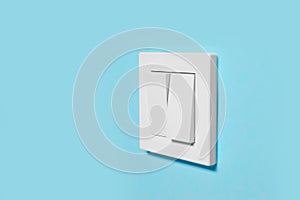 Modern plastic light switch on blue wall, space for text