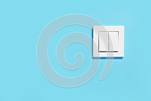 Modern plastic light switch on blue wall, space for text