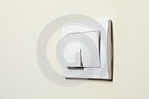 Modern plastic light switch on white wall, closeup. Space for text