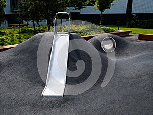 Modern playground with a metal slide inscribed in the landscape design. Playground without children.