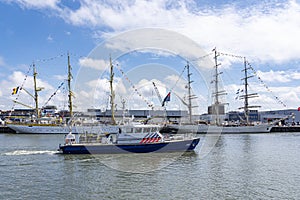 A modern police boat passes the Tallships Mircea and Shabab Oman II, in the harbour of Scheveningen during the Sail on Scheveninge