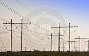 Modern power lines on a field in the evening sun