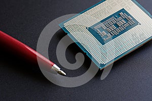 Modern powerful processor of a personal computer compared to the tip of a fountain pen. Black background. Computer assembly.