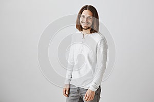 Modern prince in shiny white sweater. Portrait of attractive slender male with beard and long hair standing half-turned