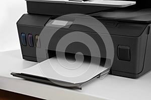Modern printer with paper on white table, closeup