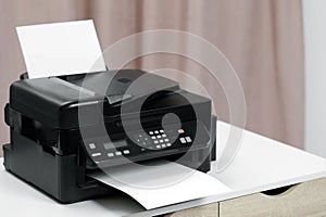 Modern printer with paper on white table indoors