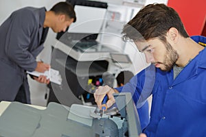 Modern printing machine operator and apprentice