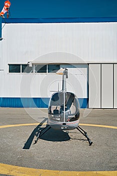 Modern private helicopter parked before metal hangar photo