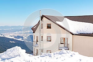 Modern private house cottage building in high mountain cliff in sunny cold frosty day. Winter beautiful