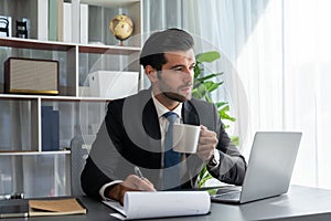 Modern professional businessman at modern office desk with coffee. fervent