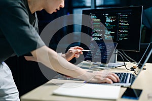 Programmer using stylus and laptop to write code at night. Coding workspace with tablet, monitor, and dark theme