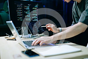 Programmer using stylus and laptop to write code at night. Coding workspace with tablet, monitor, and dark theme