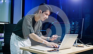 Programmer using stylus and laptop to write code at night. Coding workspace with tablet, monitor, and dark theme