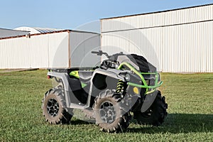 Modern quad bike in field near hangars on sunny day