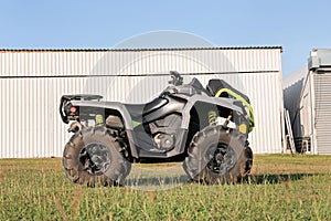 Modern quad bike in field near hangars on sunny day