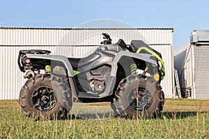 Modern quad bike in field near hangars on sunny day