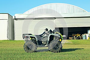 Modern quad bike in field near hangars on sunny day