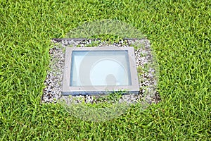 Modern quadrangular metal spotlight led lamp for outdoor use with square shape recessed in a grass floor