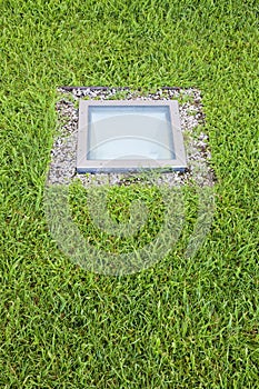 Modern quadrangular metal spotlight led lamp for outdoor use with square shape recessed in a grass floor