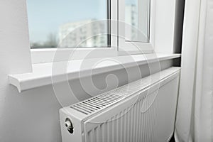 Modern radiator under window at home. Central heating system