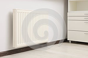 Modern radiator on white wall in room. Central heating system