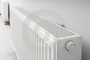 Modern radiator on white wall in room, closeup. Central heating system
