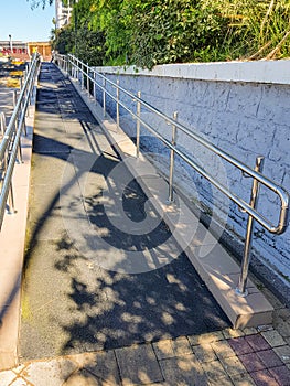 Modern ramp with shiny metal railings outdoors, wheelchair accessible, close-up, vertical