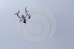 Modern RC drone flying on snow weather. Digital technology. Uav drone copter flying with digital camera in bad weather conditions.